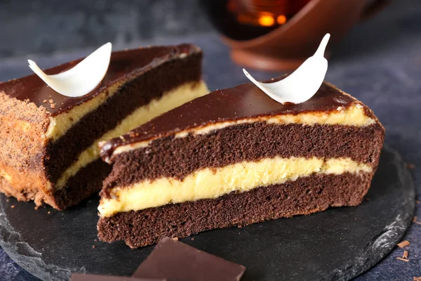 Koyu arkaplanda çikolatalı pasta parçaları olan siyah tahta, yakın plan.