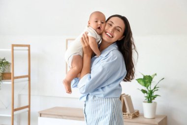Beautiful young happy mother hugging her cute little baby at home