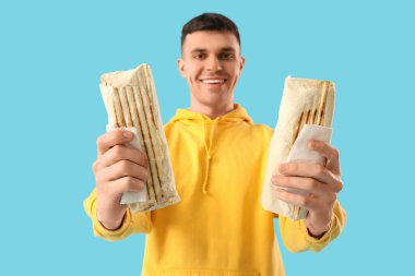 Mavi arka planda lezzetli donör kebabı olan mutlu genç adam.