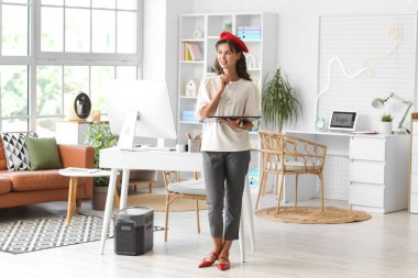 Thoughtful female designer with graphic tablet in office