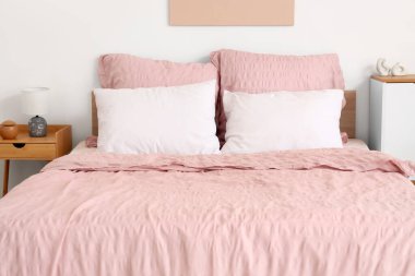 Şık pembe yataklı yatak ve yatak odasındaki komodinli.