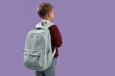 Sırt çantalı, eflatun arka planda küçük okul çocuğu.