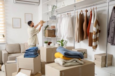 Young man with hat and wardrobe boxes in dressing room