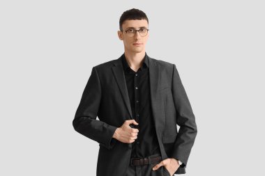 Beyaz arka planda siyah takım elbiseli yakışıklı bir iş adamı.