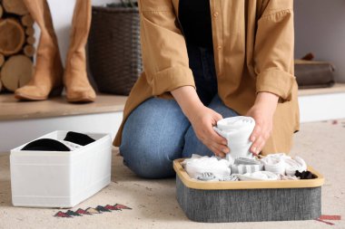 Young woman putting socks into organizer in wardrobe, closeup