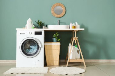 Çamaşır makinesi, sepeti ve lavabosu olan bir çamaşırhane.