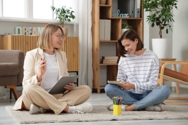 Ofiste sanat terapisi sırasında genç kız çizimi yapan bir kadın psikolog.