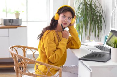Thoughtful female graphic designer working at table in office
