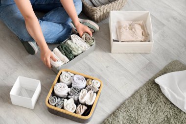 Young woman keeping her clothes in organizers at home, top view