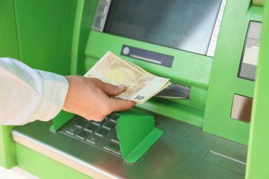 Female hand withdrawing euro banknotes from ATM, closeup