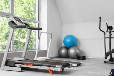 Interior of gym with treadmill and fitballs