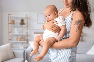 Beautiful young happy mother with her cute little baby at home, closeup