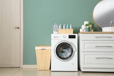 Çamaşır makinesi ve sepeti olan çamaşır odasının içi.