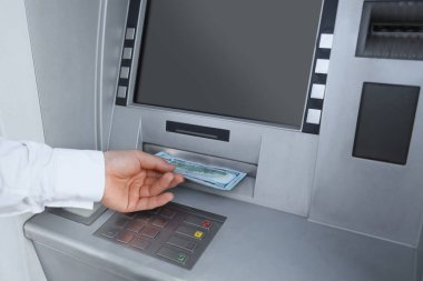 Businessman withdrawing dollar banknotes from ATM, closeup