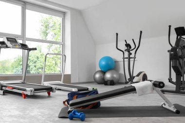 Spor salonunun içinde spor topları ve egzersiz makineleri var.