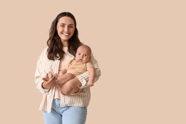 Beautiful young happy mother with her cute little baby on beige background