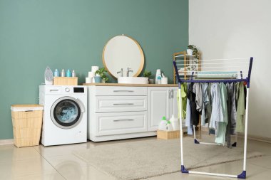 Çamaşır makinesi, lavabo ve kurutma makinesi olan bir çamaşırhane.