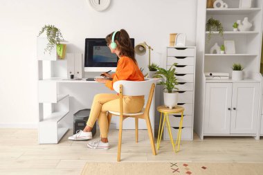 Female graphic designer in headphones working at home