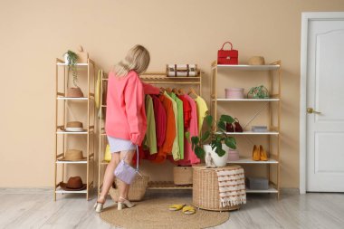 Soyunma odasında, elbise dolabının yanında genç bir kadın var.