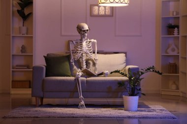 Human skeleton model with eyeglasses on sofa in dark living room