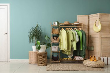 Giysi askısı, katlama perdesi ve bitkileri olan soyunma odasının içinde.