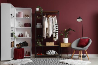 Giysi askısı, koltuk ve raf ünitesi olan soyunma odasının içinde.