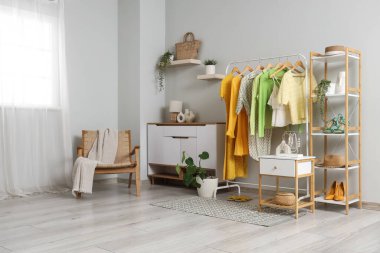 Elbise askısı, koltuk ve klozeti olan bir soyunma odası.