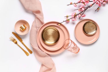 Altın çatal bıçak takımları ve gri arka planda çiçek açan dallarıyla güzel bir masa.