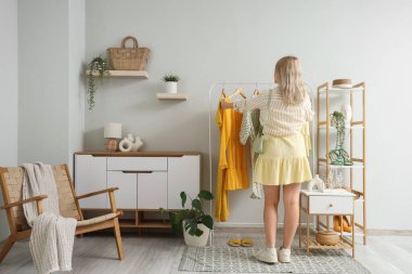 Soyunma odasında, elbise dolabının yanında genç bir kadın var.