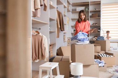 Young woman with notebook and wardrobe boxes in dressing room