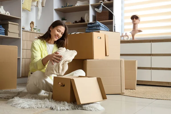 Young woman packing sweater into wardrobe box in dressing room