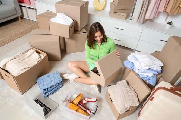 Young woman with wardrobe boxes sitting in dressing room