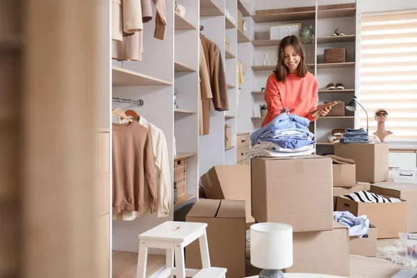 Young woman with notebook and wardrobe boxes in dressing room