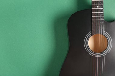 Yeşil arkaplanda siyah akustik gitar, yakın plan.