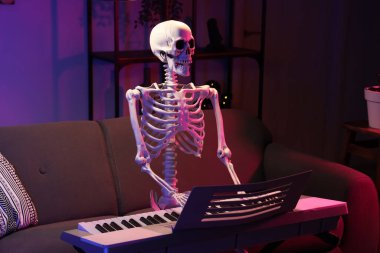 Human skeleton model with synthesizer in dark living room