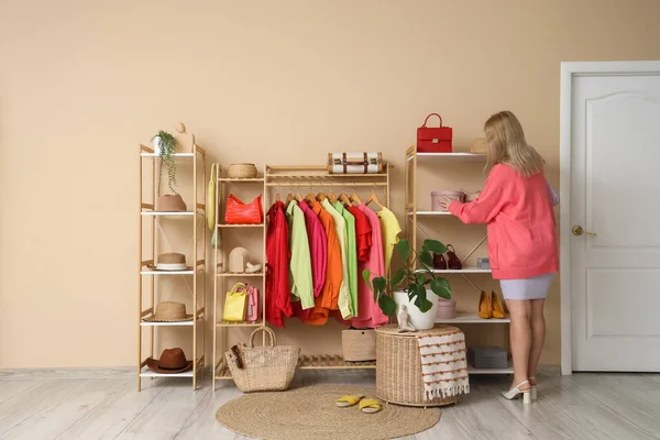 Young woman taking box from shelf in dressing room, back view