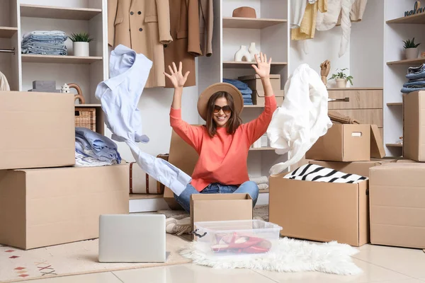 Young woman with wardrobe boxes throwing clothes in dressing room