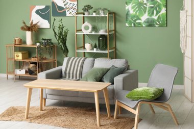 Interior of modern living room with comfortable sofa, armchair, olive pillows and wooden table