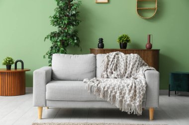 Modern interior of living room with grey comfortable sofa, plaid