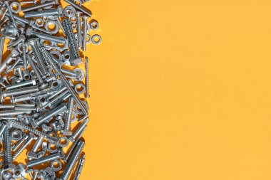 Turuncu arka planda farklı cıvatalar, vidalar ve krom fındıklar var.