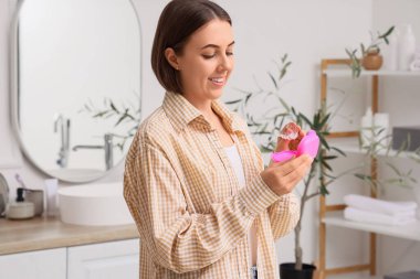 Young woman taking occlusal splint from box in bathroom