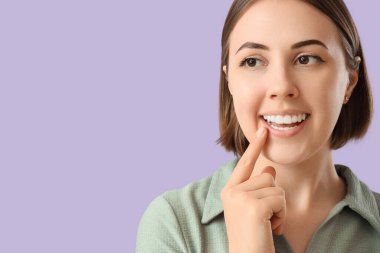 Young woman with occlusal splint on lilac background, closeup