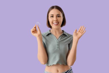 Young woman with occlusal splint on lilac background