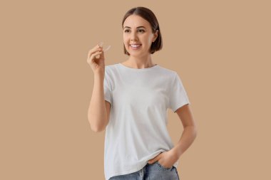 Young woman with occlusal splint on beige background