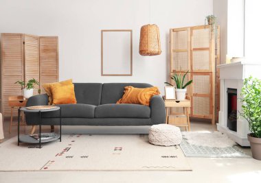 Cozy interior of living room with fireplace, sofa and folding screens