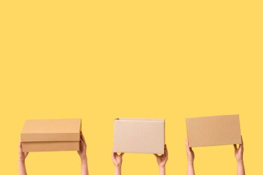 Female hands with wardrobe boxes on yellow background