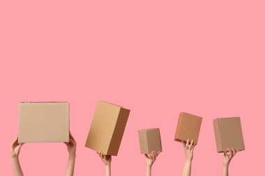 Female hands with wardrobe boxes on pink background