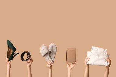 Female hands with wardrobe box, belt, shoes and jeans on beige background