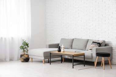 Interior of light living room with window, grey sofa and table