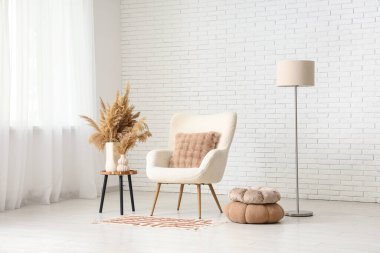 Aydınlık oturma odasının içinde koltuk, masa ve lamba var.